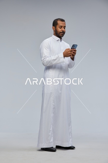 Saudi Man in White Thobe Using Smartphone in Studio