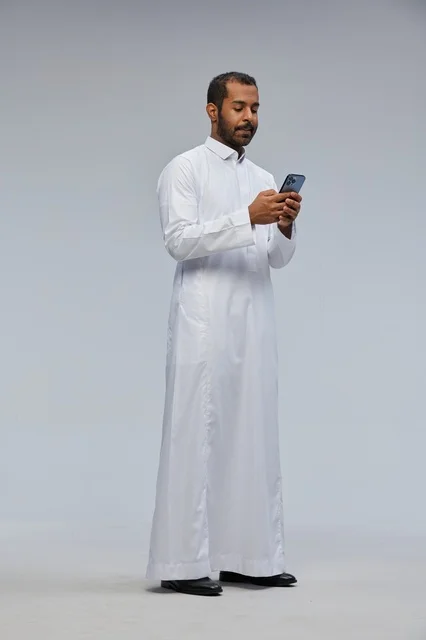 رجل سعودي بالثوب الأبيض يستخدم الهاتف في الاستوديو