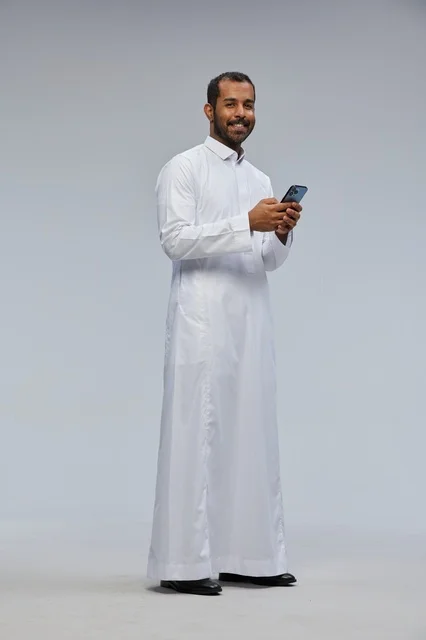 رجل سعودي بالثوب الأبيض يستخدم الجوال في استوديو