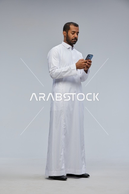 Saudi Man in Thobe Using Smartphone Studio Shot