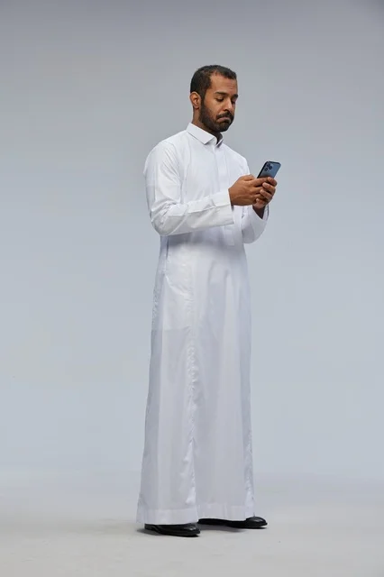 Saudi Man in White Thobe Using Smartphone Studio