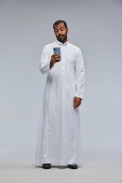 Saudi Man in Traditional Thobe Using Smartphone in Studio