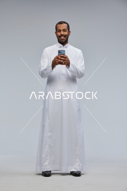 Saudi Man in White Thobe Using Smartphone in Studio