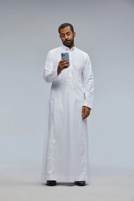 Saudi Man in White Thobe Using Smartphone in Studio
