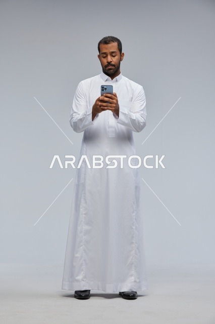 Saudi Man in White Thobe Using Smartphone in Studio