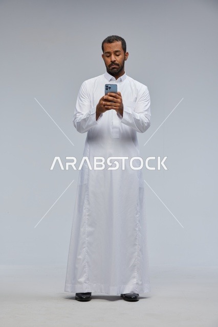 Saudi Man in White Thobe Using Smartphone in Studio