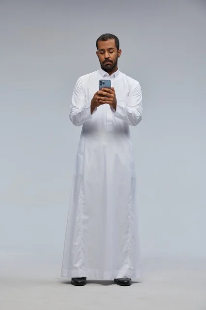 Saudi Man in White Thobe Using Smartphone in Studio