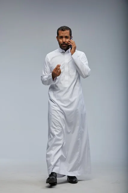 رجل سعودي يتحدث عبر الهاتف بالثوب الأبيض التقليدي