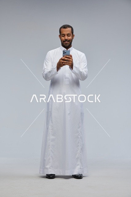 Saudi Man in White Thobe Using Smartphone in Studio