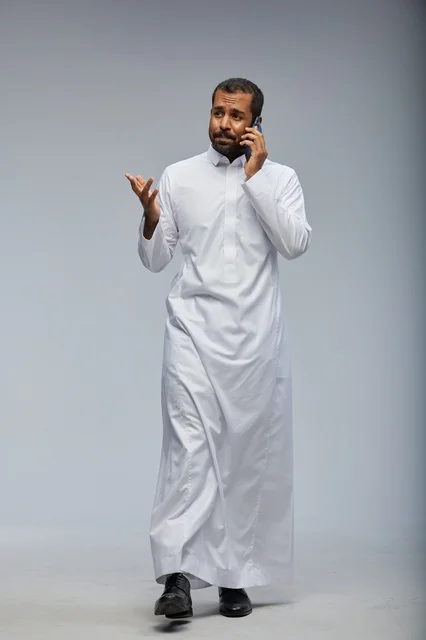 Saudi Man in White Thobe Talking on Smartphone Studio