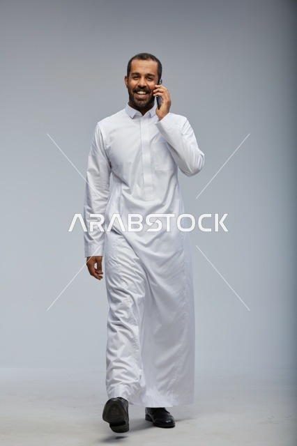 Saudi Man in White Thobe Talking on Smartphone