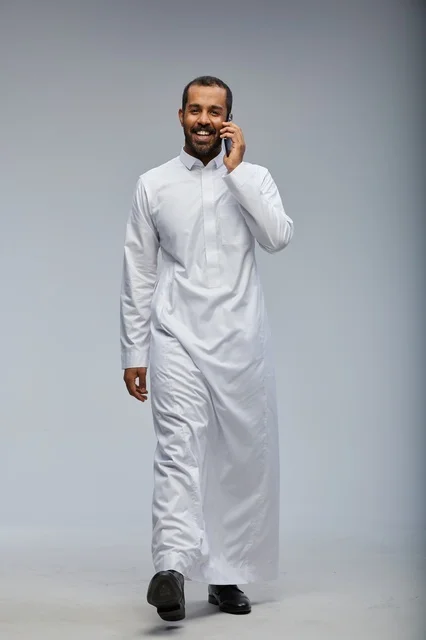 Saudi Man in White Thobe Talking on Smartphone