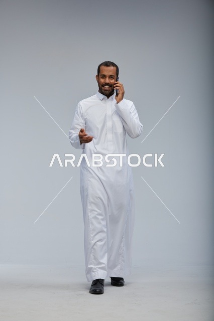 رجل سعودي بالثوب الأبيض يتحدث بالهاتف الذكي