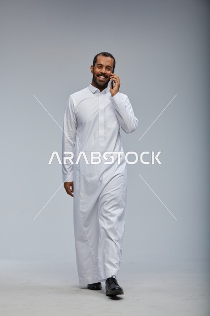 Saudi Man in White Thobe Talking on Smartphone