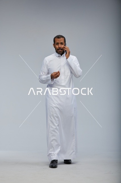 Saudi Man in White Thobe Talking on Smartphone Studio