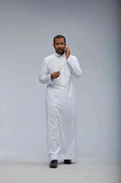 Saudi Man in White Thobe Talking on Smartphone Studio