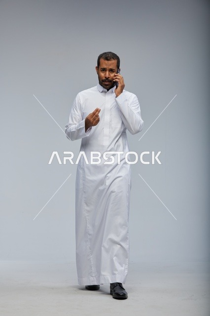 Saudi Man in White Thobe Talking on Smartphone Studio