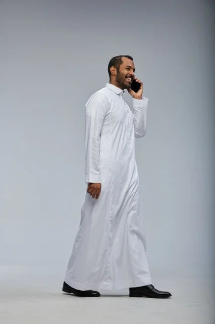 رجل سعودي بالثوب الأبيض يتحدث بالهاتف الذكي