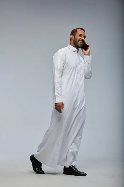 رجل سعودي بالثوب الأبيض يتحدث عبر هاتف ذكي تصوير استوديو