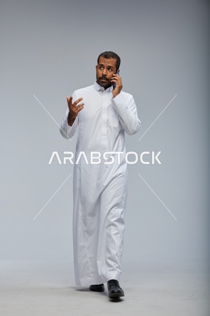 Saudi Man in White Thobe Talking on Smartphone