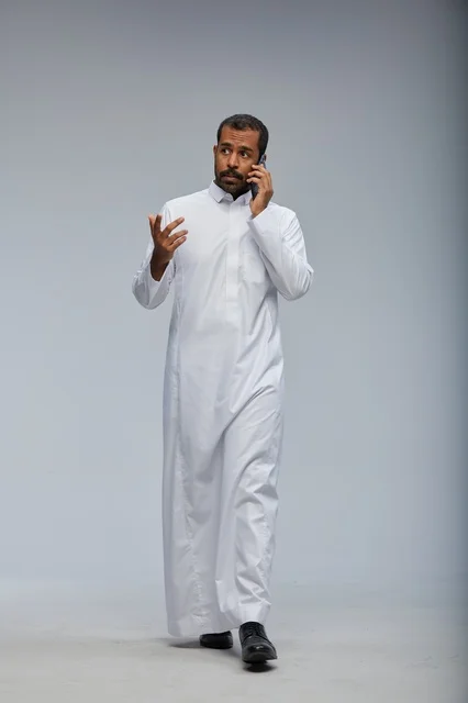 رجل سعودي بالثوب الأبيض يتحدث بالجوال في الاستوديو