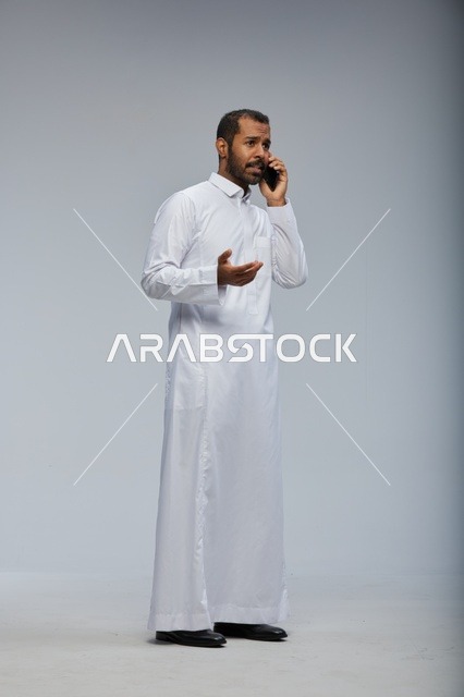 Saudi Man in White Thobe Talking on Smartphone