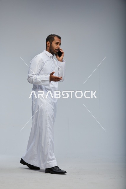 Saudi Man in White Thobe Talking on Smartphone Studio