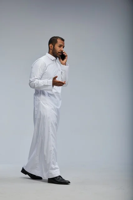 Saudi Man in White Thobe Talking on Smartphone Studio