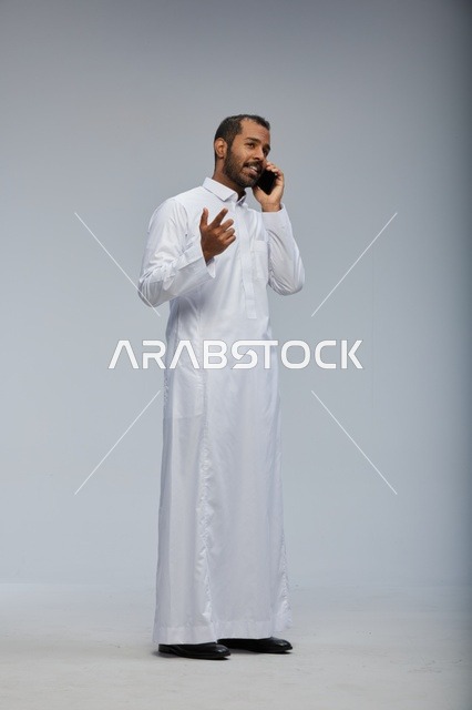 Saudi Man in White Thobe Talking on Smartphone Studio