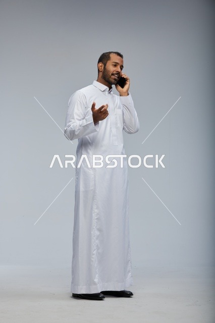 Saudi Man in White Thobe Talking on Smartphone