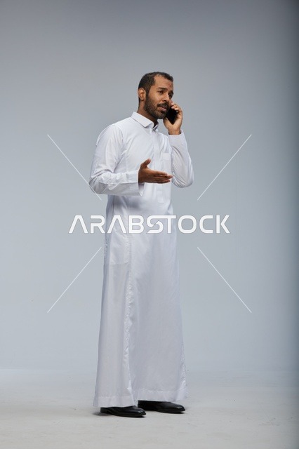 Saudi Man in White Thobe Talking on Smartphone