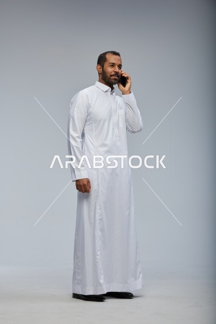 Saudi Man in White Thobe Talking on Smartphone Studio