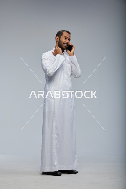 Saudi Man in White Thobe Talking on Smartphone Studio Shot