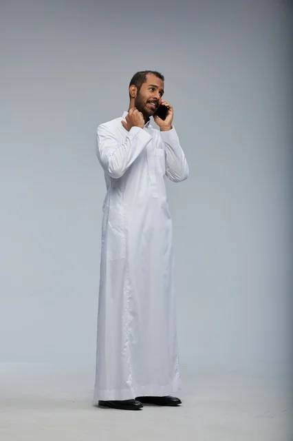Saudi Man in White Thobe Talking on Smartphone Studio Shot
