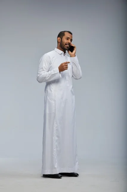 Saudi Man in White Thobe Talking on Smartphone