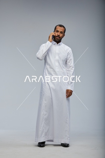 Saudi Man in White Thobe Talking on Smartphone Studio