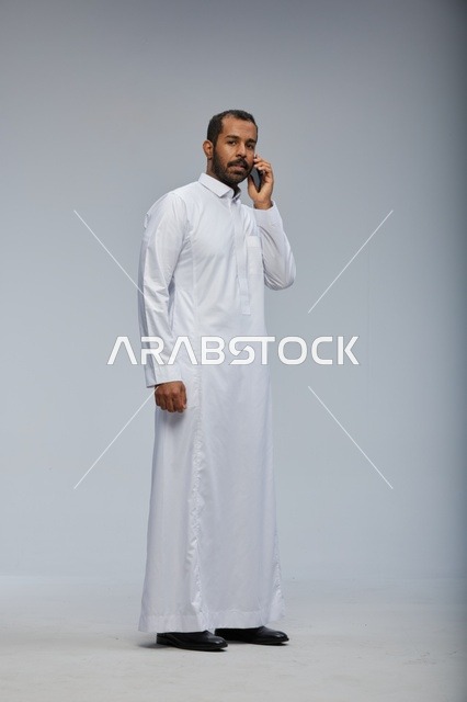 Saudi Man in White Thobe Talking on Smartphone in Studio