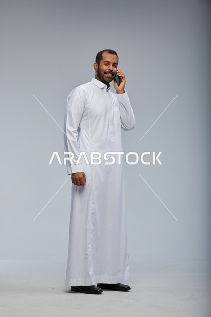 Saudi Man in White Thobe Talking on Smartphone Studio