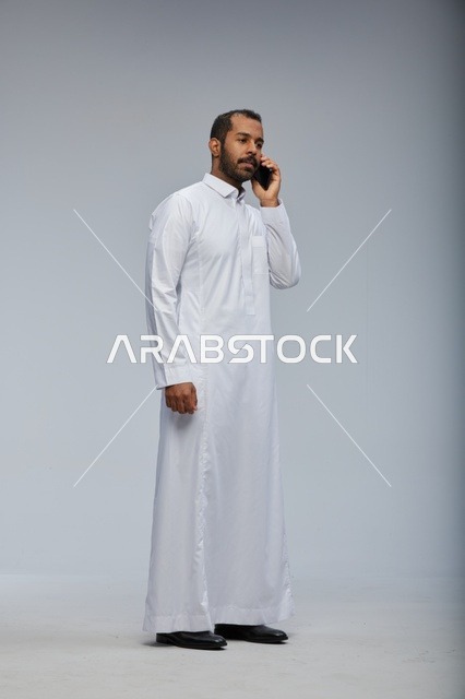 رجل سعودي بالثوب الأبيض يتحدث بالجوال