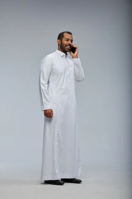 Saudi Man in White Thobe Talking on Smartphone