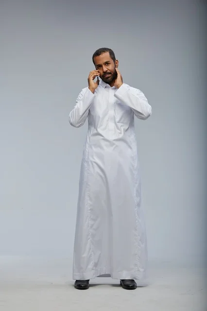 Saudi Man in White Thobe Talking on Smartphone