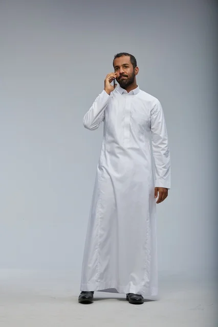 Saudi Man in White Thobe Talking on Smartphone