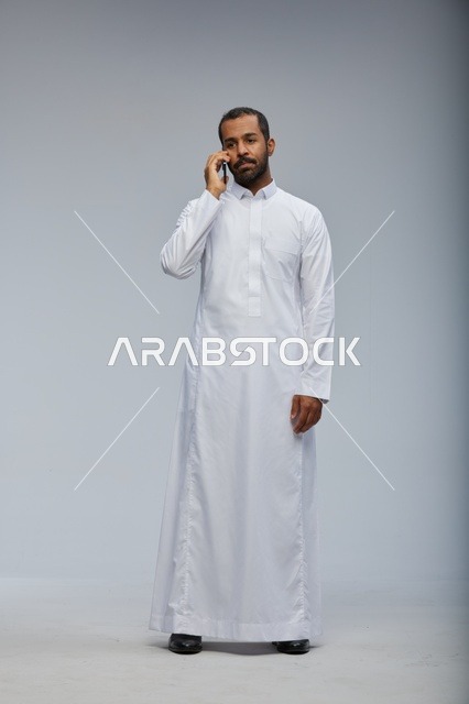 Saudi Man in White Thobe Talking on Smartphone Studio
