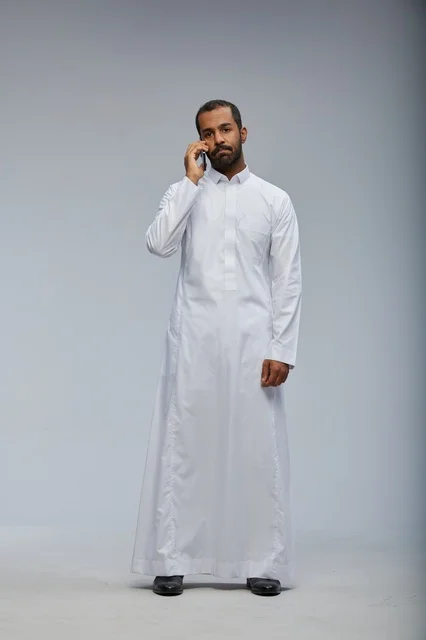 Saudi Man in White Thobe Talking on Smartphone