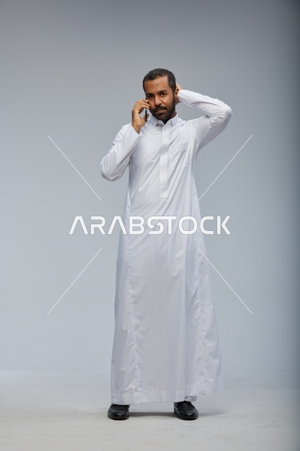 رجل سعودي بالثوب الأبيض يتحدث بالجوال في الاستوديو