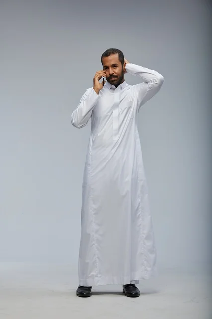 رجل سعودي بالثوب الأبيض يتحدث بالجوال في الاستوديو