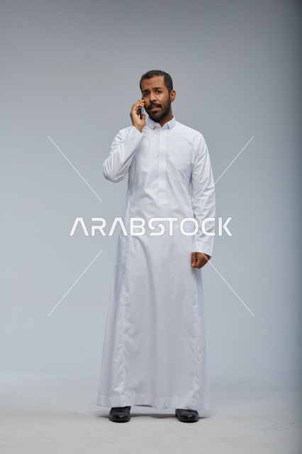 Saudi Man in White Thobe Talking on Smartphone Studio
