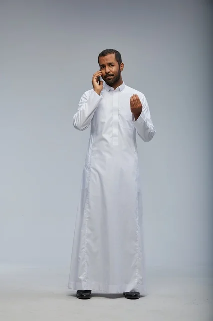 Saudi Man in White Thobe Talking on Smartphone