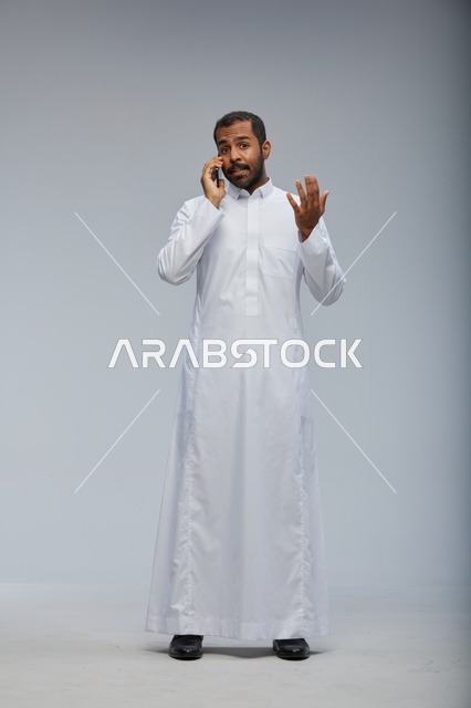 Saudi Man in White Thobe Talking on Smartphone