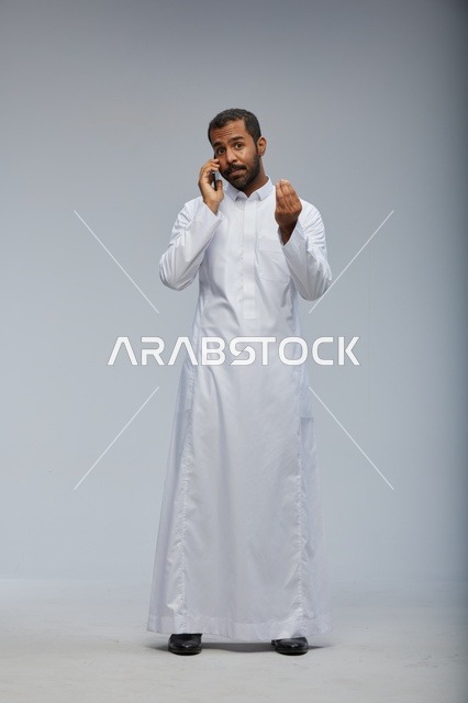 رجل سعودي يرتدي الثوب الأبيض يتحدث بالجوال في استوديو